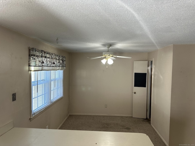 spare room featuring carpet floors, ceiling fan, a textured ceiling, and baseboards