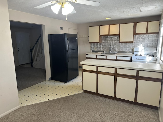 kitchen with white range with gas stovetop, light countertops, a sink, and freestanding refrigerator