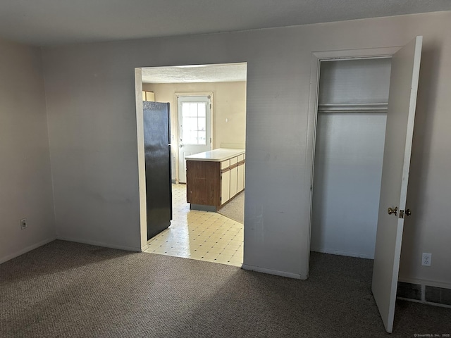 unfurnished bedroom with light carpet, visible vents, a closet, and freestanding refrigerator