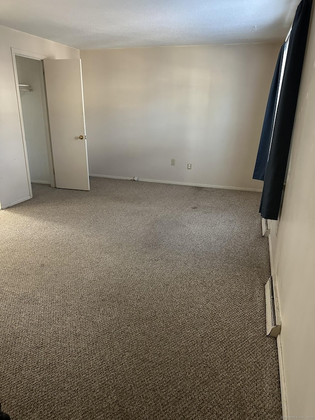 empty room featuring a textured ceiling, carpet, visible vents, and baseboards