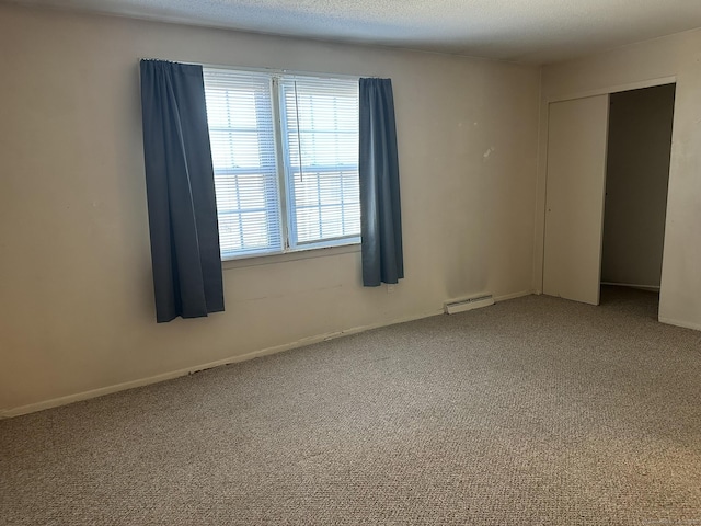 spare room featuring carpet floors, a baseboard radiator, a textured ceiling, and baseboards