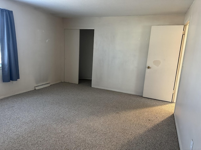 carpeted spare room with a baseboard heating unit