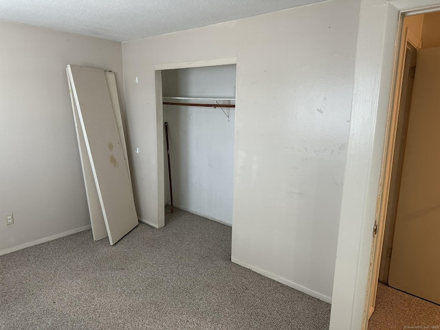 unfurnished bedroom featuring a textured ceiling, carpet, and baseboards