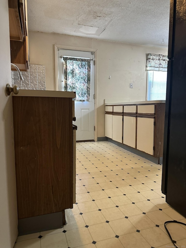 kitchen featuring a textured ceiling, light floors, and freestanding refrigerator