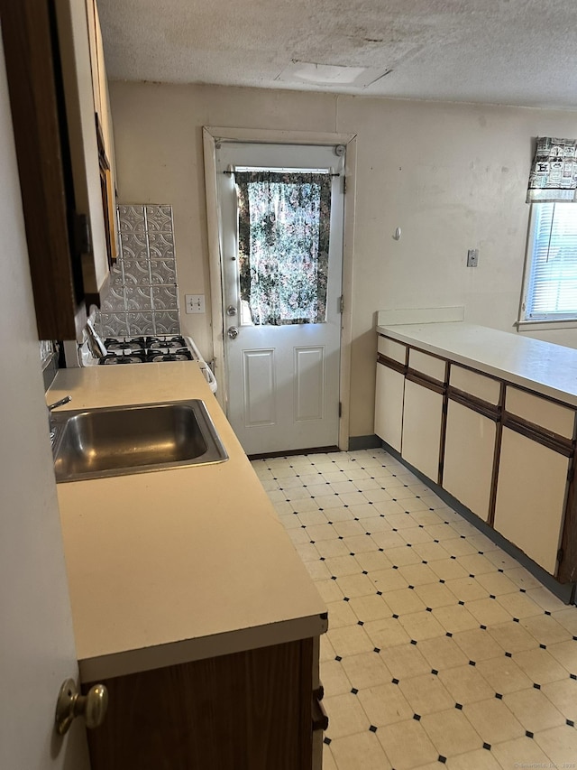 kitchen featuring light floors, a textured ceiling, light countertops, and a sink