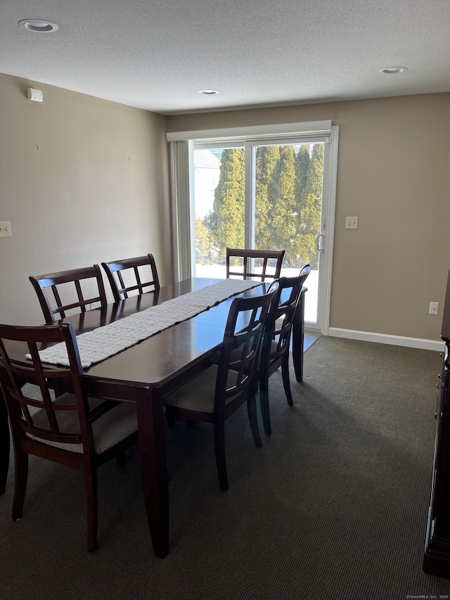 carpeted dining room with a textured ceiling and baseboards