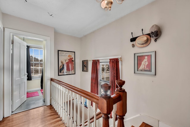 hall with baseboards, an upstairs landing, and wood finished floors