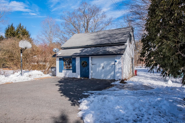 view of front facade featuring an outbuilding, aphalt driveway, and a garage