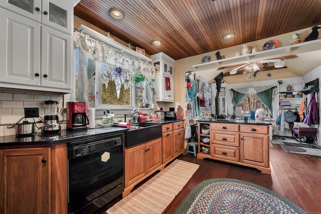 kitchen with dark wood-style floors, glass insert cabinets, dishwasher, dark countertops, and tasteful backsplash