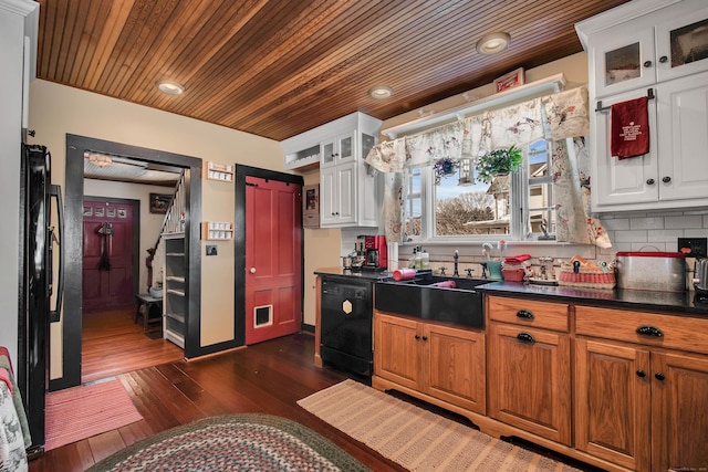 kitchen featuring black appliances, dark wood-type flooring, white cabinetry, dark countertops, and backsplash