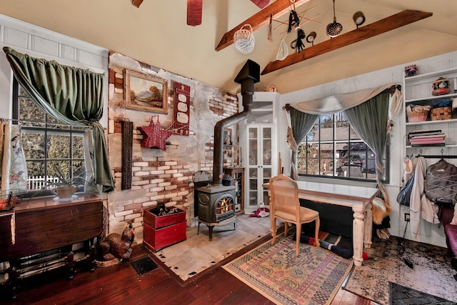 interior space with lofted ceiling, brick wall, a wood stove, and hardwood / wood-style flooring