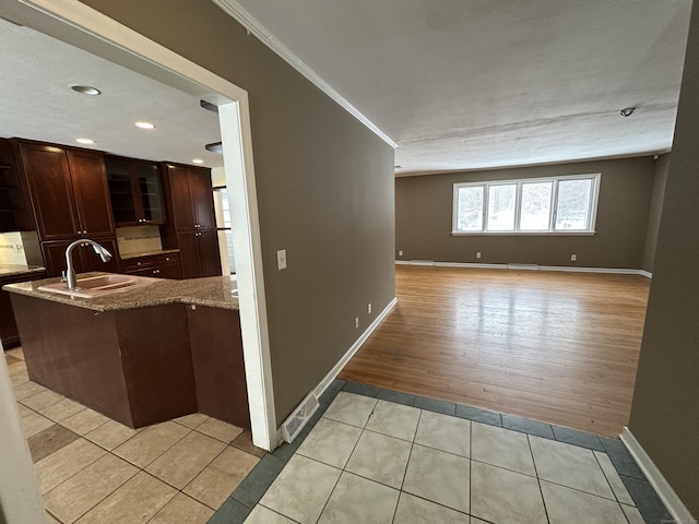 159 Tom Swamp Rd, Hamden, CT 06518 - kitchen featuring crown molding, light tile patterned floors, glass insert cabinets, a sink, and light stone countertops
