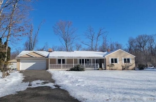 single story home featuring driveway, covered porch, a garage, and a chimney