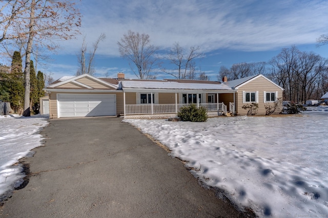 ranch-style home featuring driveway, an attached garage, a chimney, and a porch