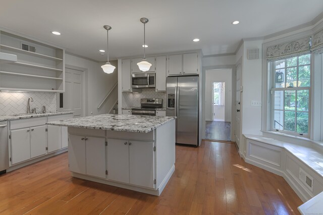 kitchen with decorative light fixtures, open shelves, stainless steel appliances, visible vents, and a kitchen island