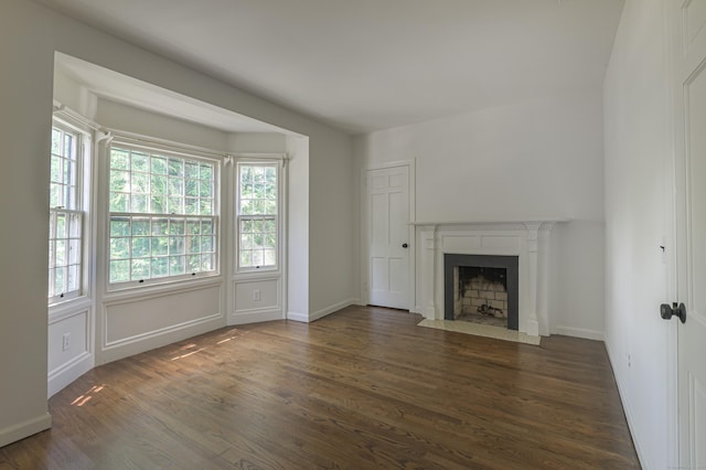 unfurnished living room featuring dark wood-style floors, a fireplace with flush hearth, and baseboards