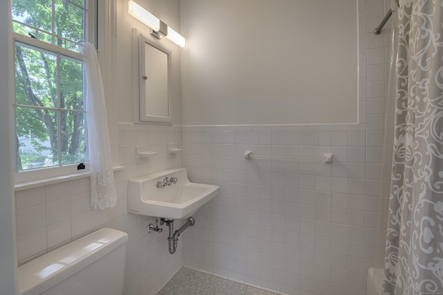 full bath with toilet, tile walls, a wealth of natural light, and a shower with shower curtain