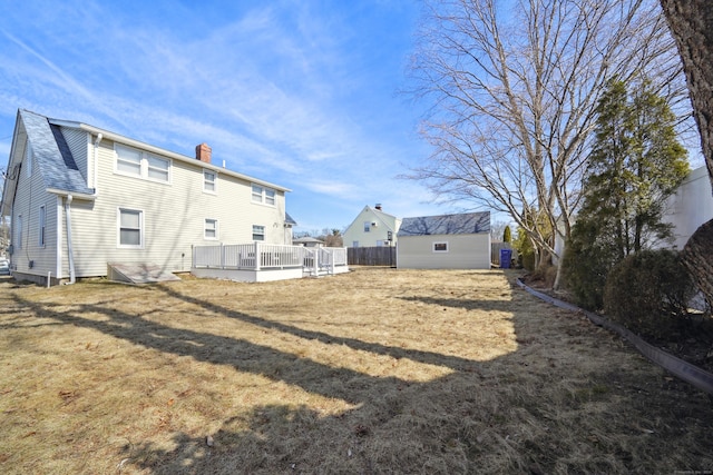 back of house with a shingled roof, fence, a chimney, a yard, and an outdoor structure