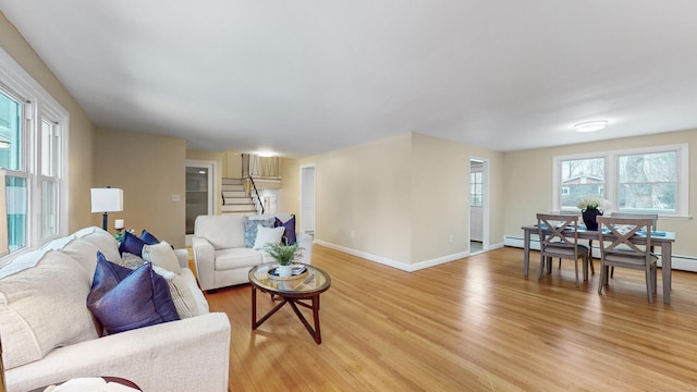 living room with light wood-type flooring, stairs, and baseboards