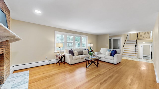 living room featuring a baseboard heating unit, light wood finished floors, stairway, and a fireplace