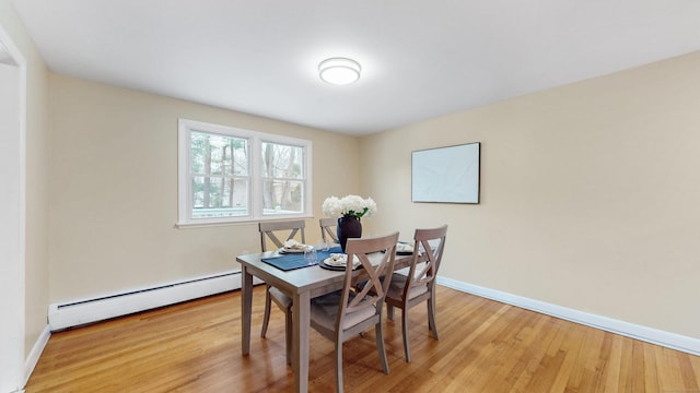 dining area featuring a baseboard radiator, light wood-style flooring, and baseboards