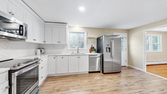 kitchen featuring a baseboard heating unit, stainless steel appliances, a sink, light wood-style floors, and light countertops