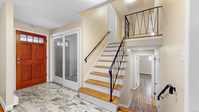 entrance foyer featuring marble finish floor, baseboards, stairway, and baseboard heating