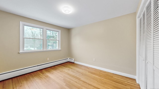 unfurnished bedroom with a closet, a baseboard radiator, light wood-style flooring, and baseboards