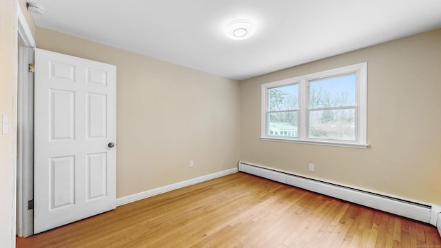 empty room with a baseboard radiator, light wood-style flooring, and baseboards