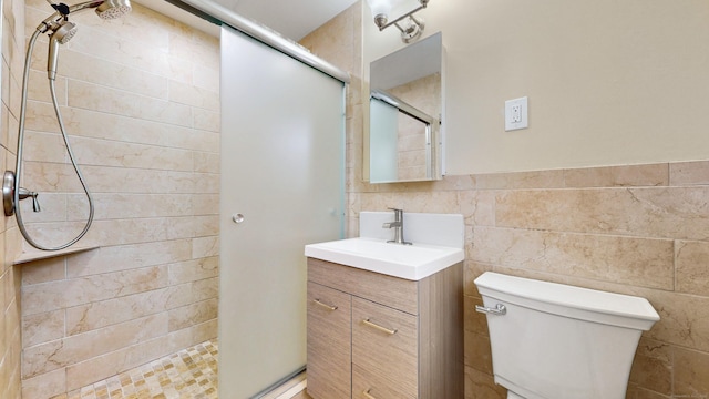 bathroom featuring toilet, vanity, tile walls, wainscoting, and a stall shower