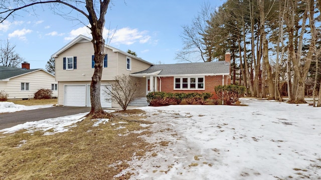 view of front of home featuring driveway, a chimney, and brick siding