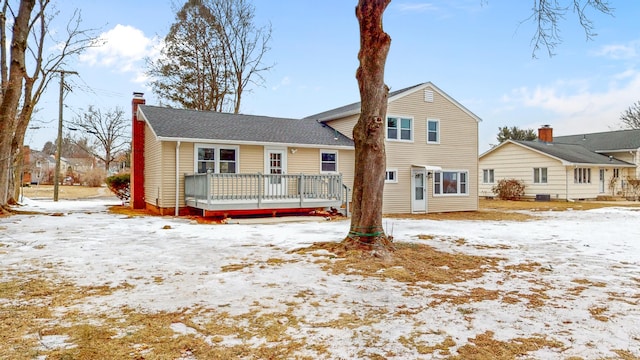 snow covered back of property featuring a chimney and a deck