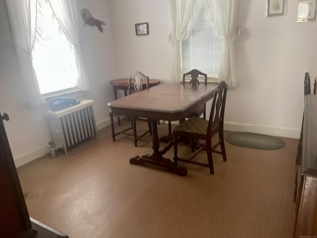 carpeted dining room featuring radiator and baseboards