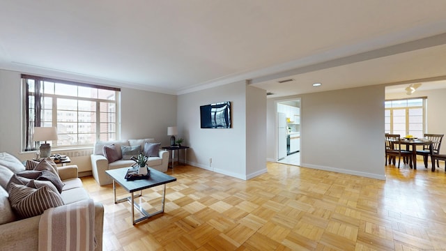 living room with visible vents, crown molding, a wealth of natural light, and baseboards