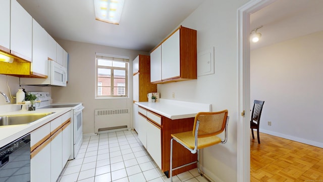 kitchen featuring white appliances, a sink, white cabinets, light countertops, and radiator heating unit