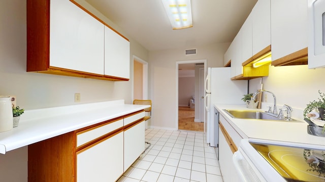 kitchen featuring light tile patterned flooring, white appliances, a sink, visible vents, and light countertops