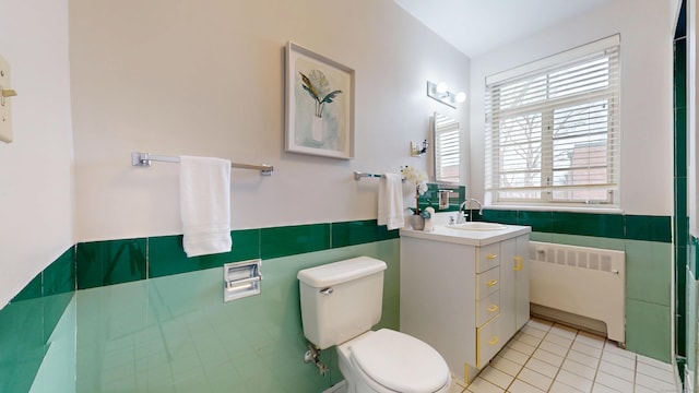 bathroom with tile walls, radiator, toilet, vanity, and tile patterned flooring