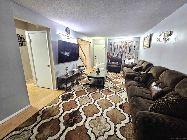 living area featuring a textured ceiling, stairway, and light wood-style flooring