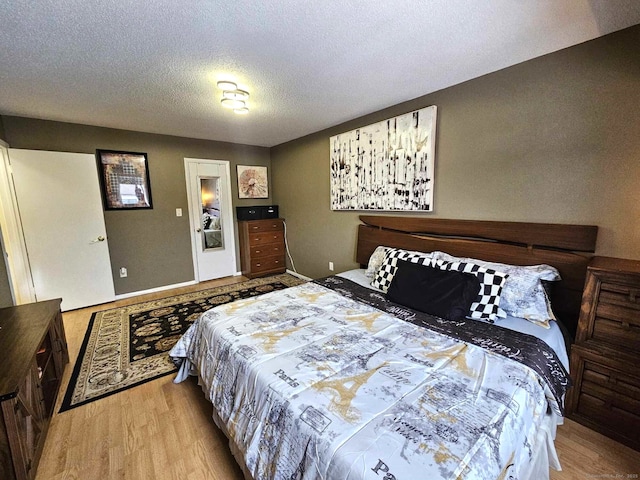 bedroom with a textured ceiling and light wood finished floors