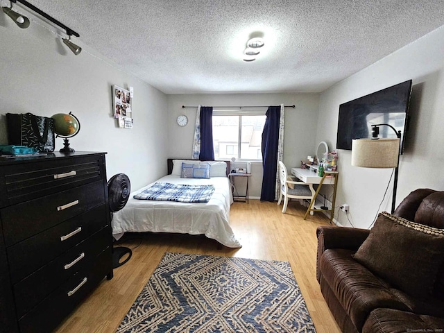 bedroom with light wood-type flooring and a textured ceiling