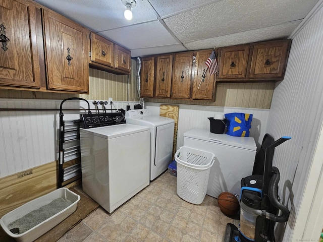 clothes washing area featuring light floors, washer and clothes dryer, and cabinet space