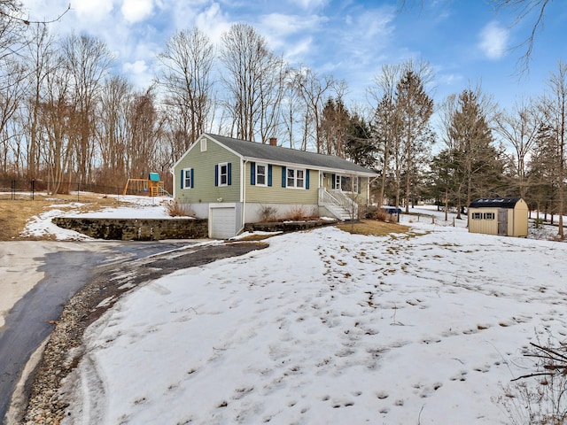 view of front of home with a garage, a chimney, an outdoor structure, a shed, and a playground