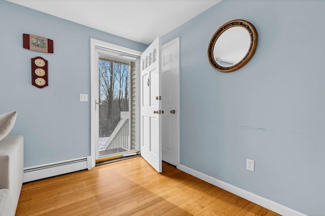 entryway with light wood-type flooring, baseboards, and a baseboard heating unit