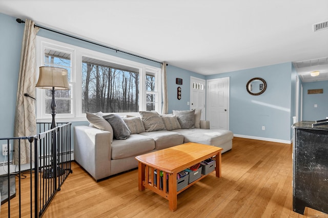 living area featuring visible vents, a baseboard radiator, light wood-style flooring, and baseboards