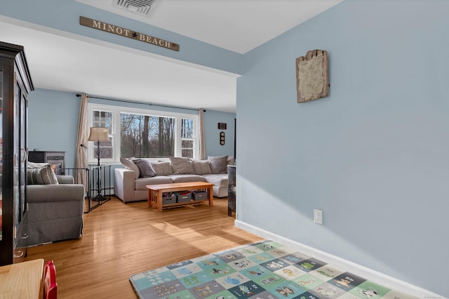 living area featuring light wood-style floors, baseboards, and visible vents