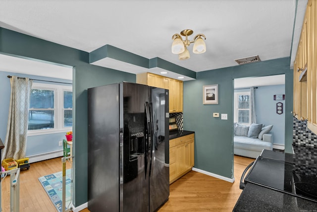 kitchen with dark countertops, visible vents, light brown cabinetry, light wood-style floors, and black appliances