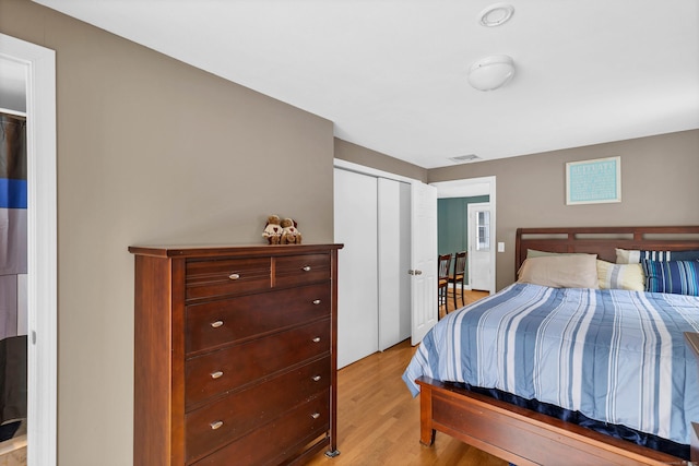 bedroom with light wood-style flooring, visible vents, and a closet