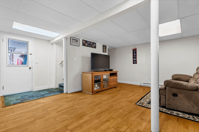 interior space featuring a baseboard heating unit, wood finished floors, a paneled ceiling, and baseboards