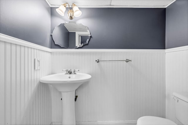 bathroom featuring toilet, a sink, and wainscoting