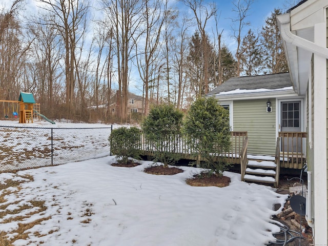 yard covered in snow with a playground and a wooden deck